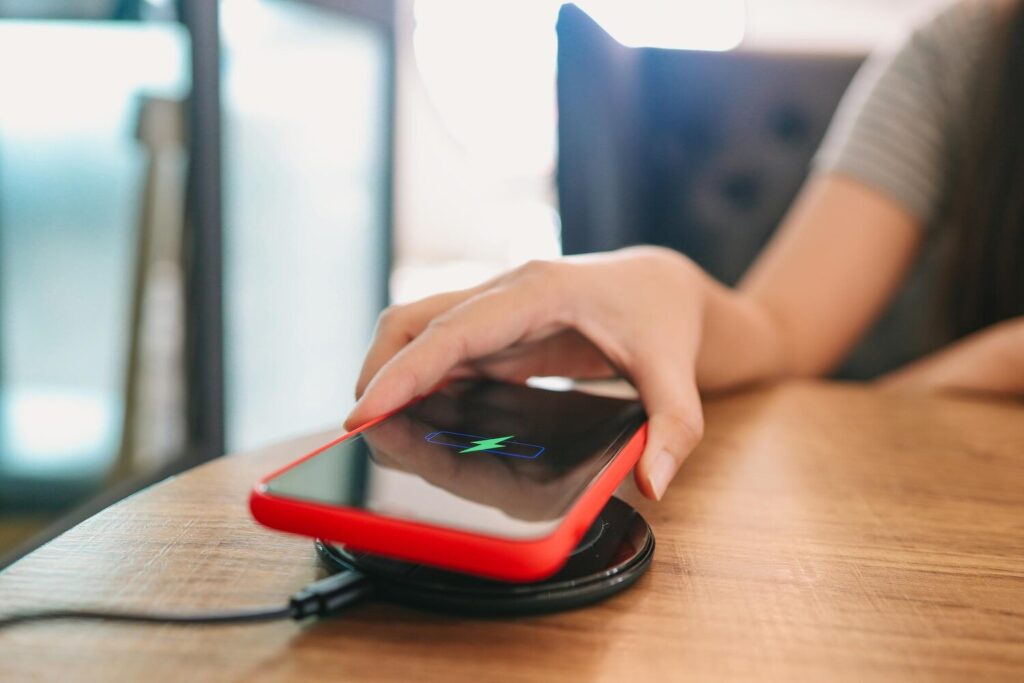 Charging mobile phone battery with wireless charging device table smartphone charging charging pad mobile phone near wireless charger modern lifestyle concept 1715 12275